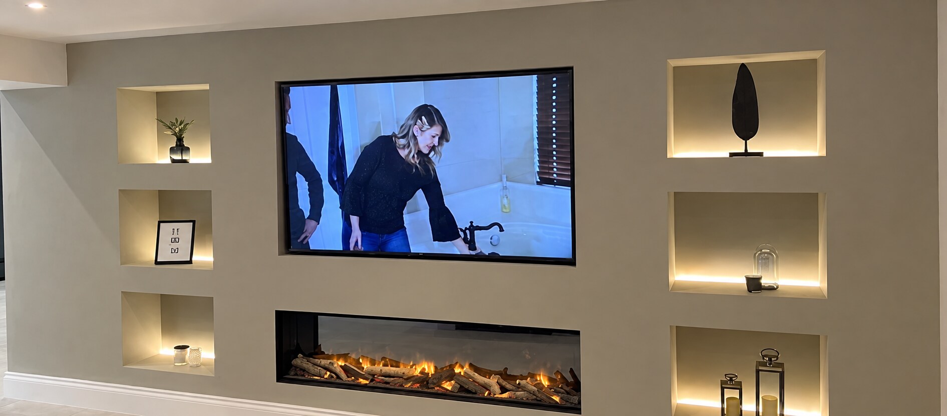 Finished neutral media wall with illuminated display niches and inset fireplace
