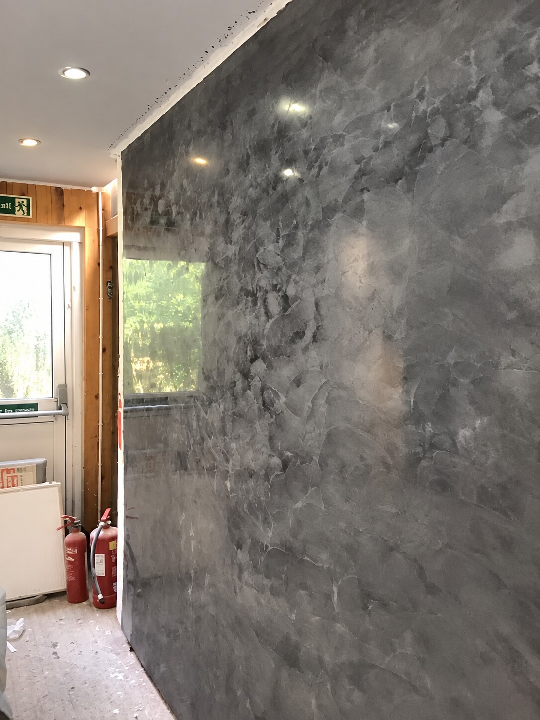 Dark grey polished decorative plaster feature wall reflecting ceiling lights