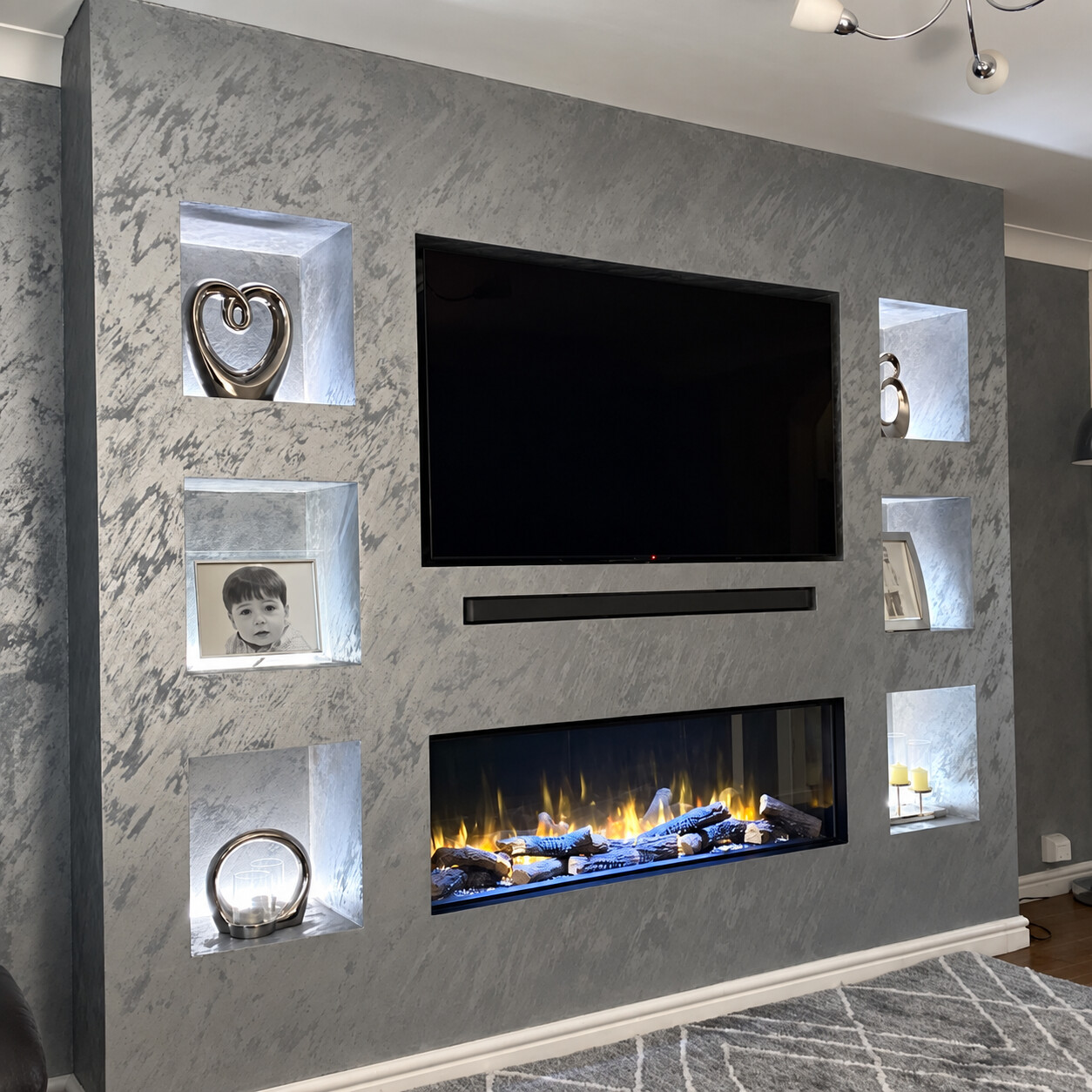 Grey polished plaster media wall with illuminated display niches and fireplace, completed by Cleals Premium Plastering